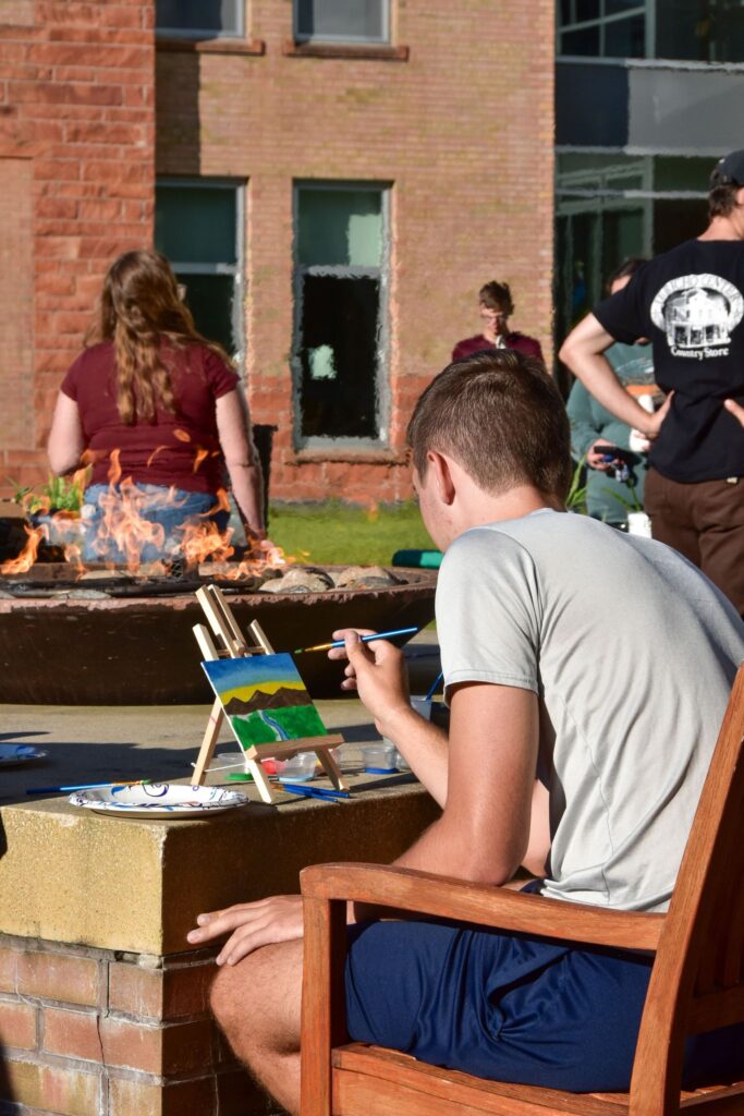 Picture of student painting at Clarkson firepit event.