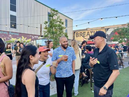 Four people chatting and laughing outdoors at a networking event.
