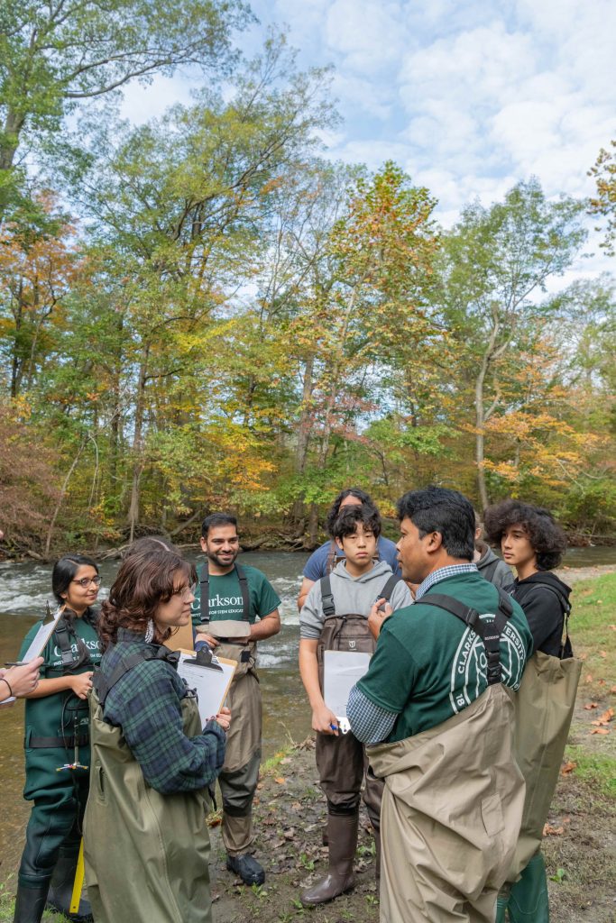 Professor and students standing in a river collecting samples to test for microplastics