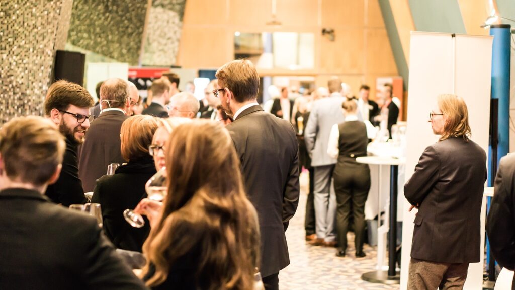 Several people gather in small groups to network in a hallway at a conference