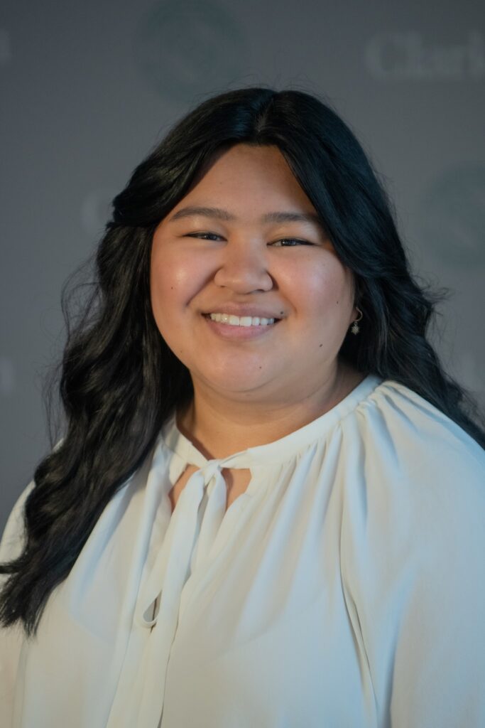 Professional photo of a young Phillipeno professional woman with long wavy black hair wearing a white blouse that ties at the neck. 