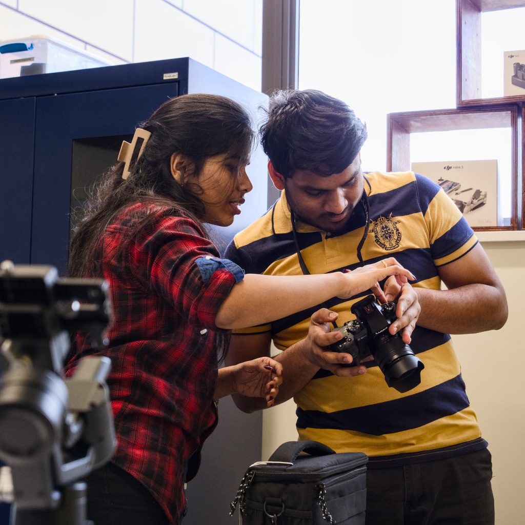 Two students use a camera in the Makers' Loft.
