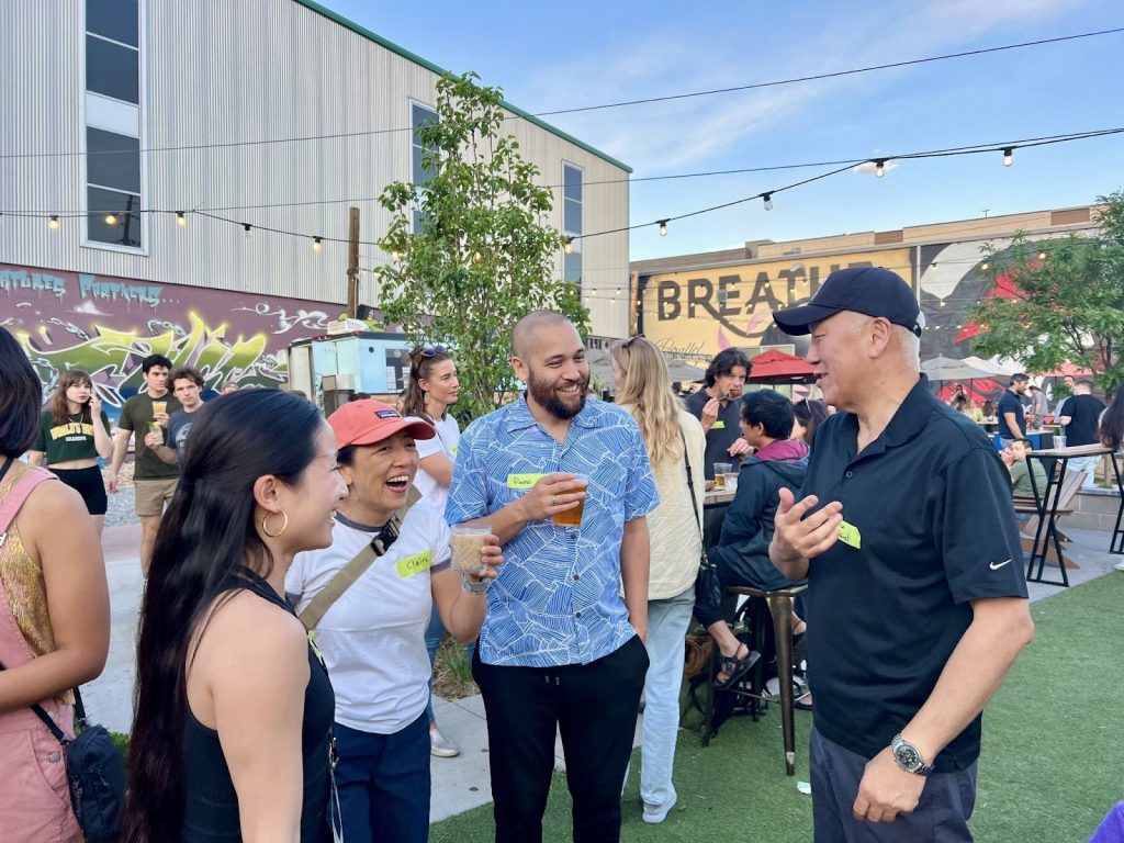 Four people chatting and laughing outdoors at a networking event.