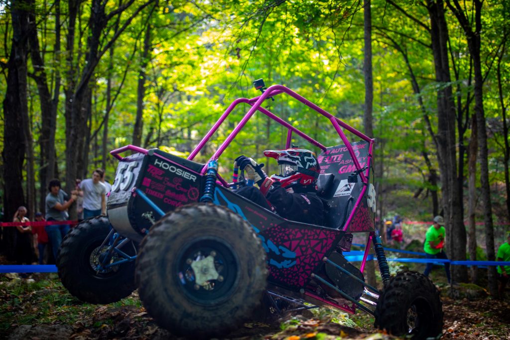 A BAJA buggy navigates rough terrain in a forest
