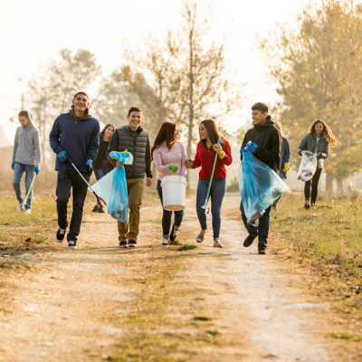 Image of several young adults walking and picking up items from the ground.