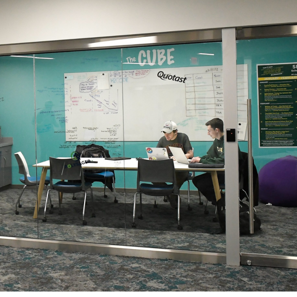 Photo of two students working at a table inside The CUBE