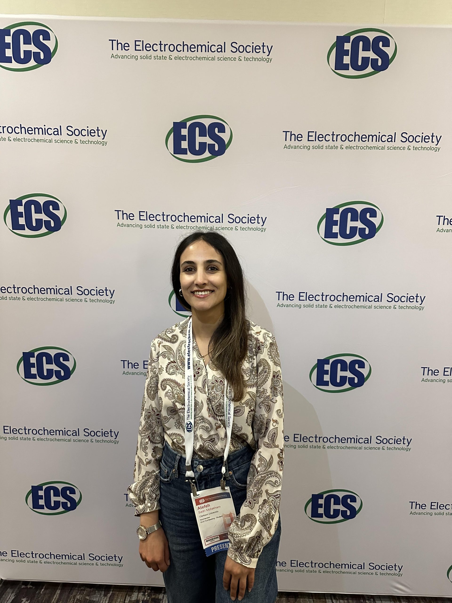 Atefeh Sadri Mofakham poses in front of a banner for The Electrochemical Society