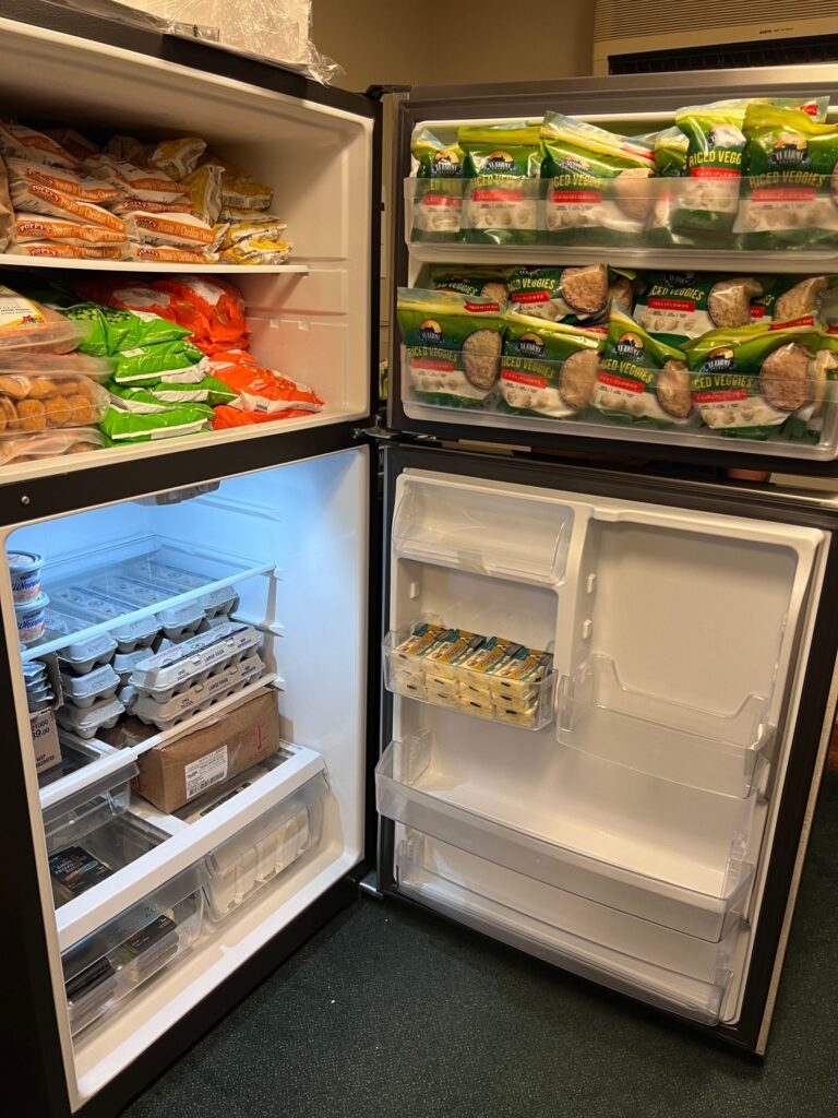 Open refrigerator and freezer showing various foods including vegetables in the freezer and eggs and cheese in the refrigerator.