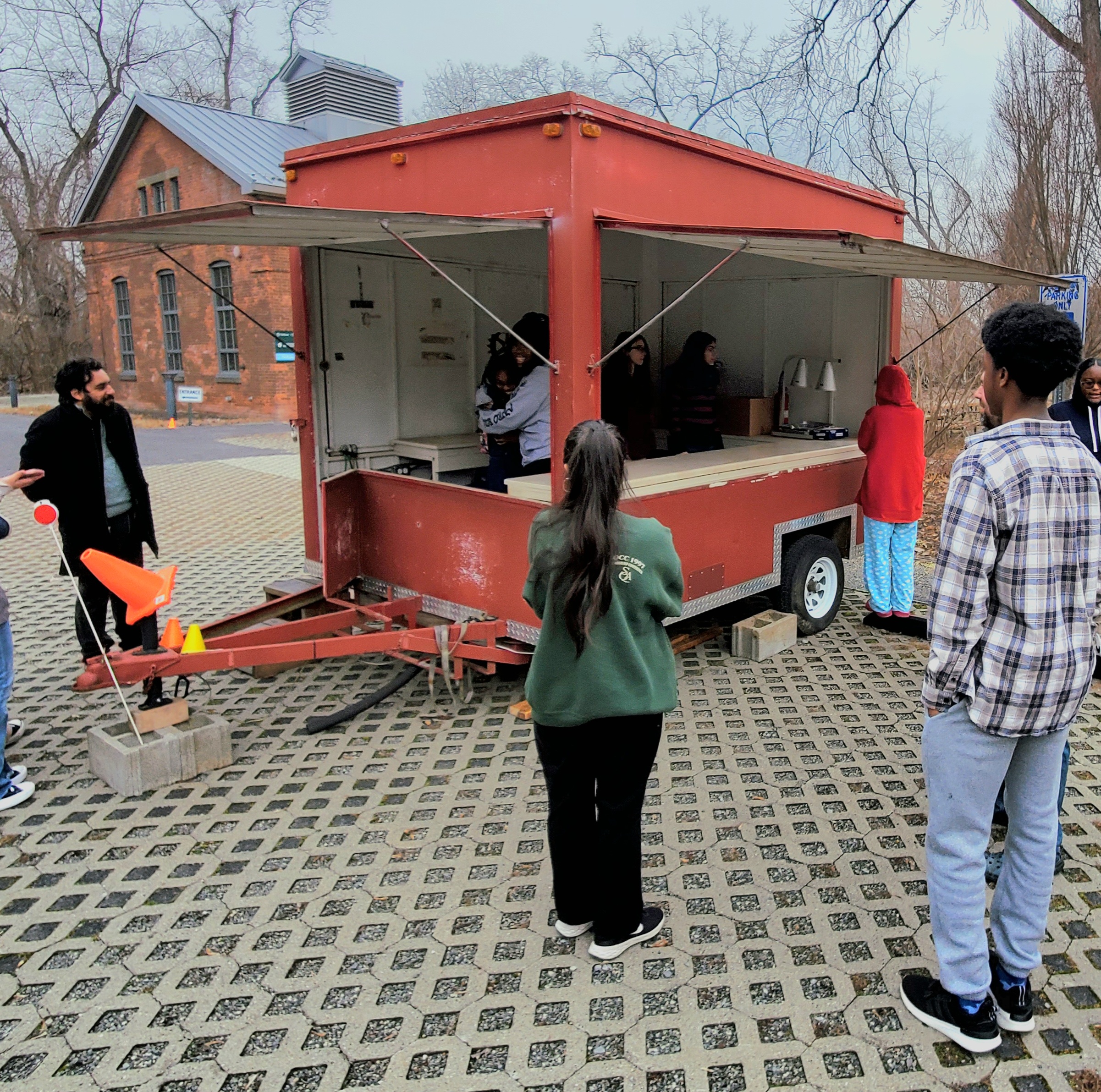 Four students stand in a parking lot around a food truck