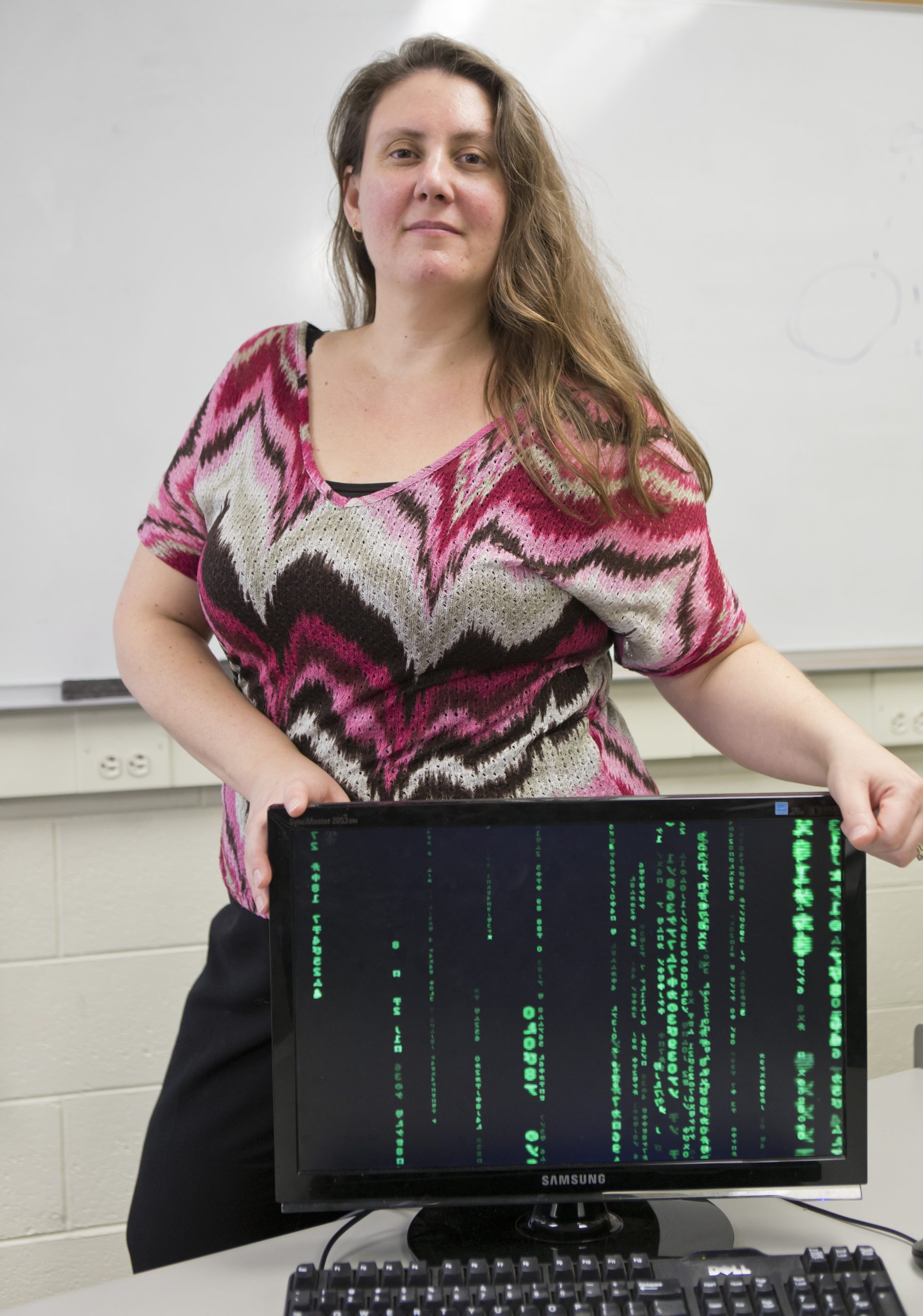 Jeanna Matthews posed in front of a computer screen showing code.