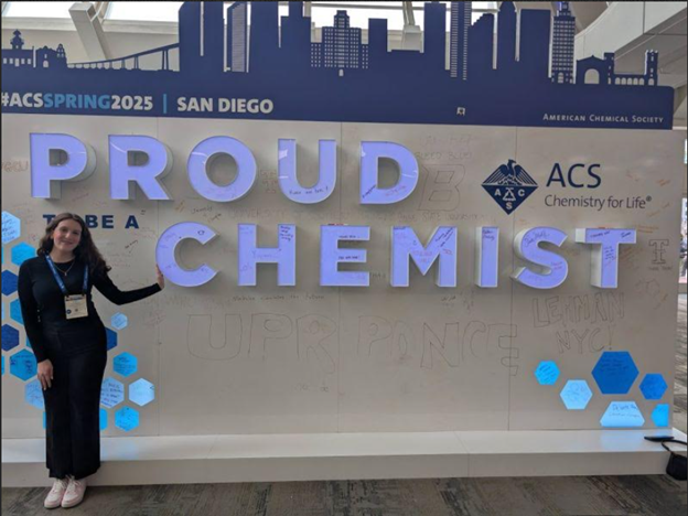 Kirby Davidson stands next to a large "proud chemist" sign.
