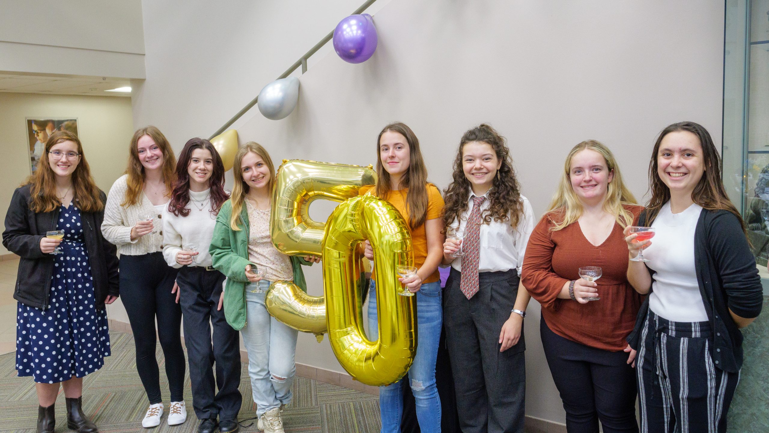 Eight women engineering students pose with an inflatable "50" during a celebration of 50 years of SWE at Clarkson.