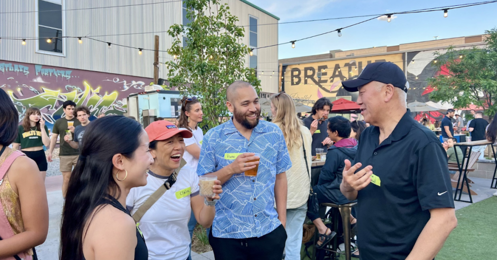 Four people chatting and laughing outdoors at a networking event.