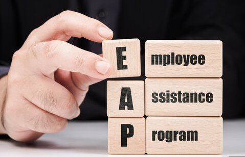 Hand placing blocks to complete the spelling of Employee Assistance Program.