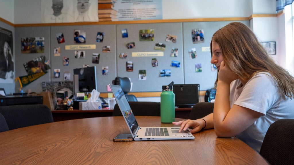 A student leans on her hand while she uses her laptop