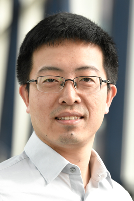 Close-up portrait of Xiaocun Lu in white, open-collared shirt